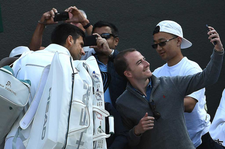 Djokovic melayani permintaan foto dari penggemarnya saat akan meninggalkan lapangan.  AFP/Glyn Kirk