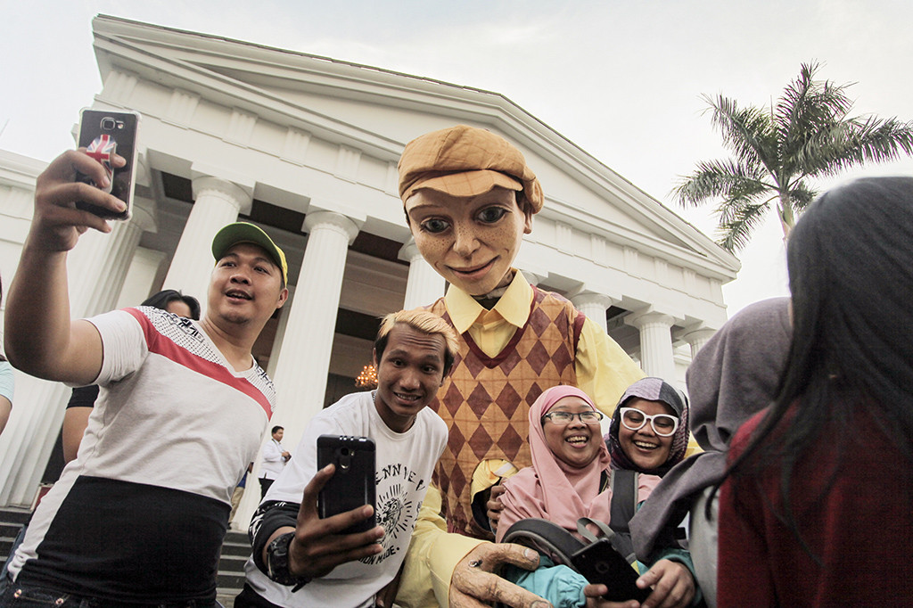 Warga berfoto dengan ondel-ondel atau boneka raksasa Les Grandes Personnes usai pertunjukan di kawasan Kota Tua, Jakarta.