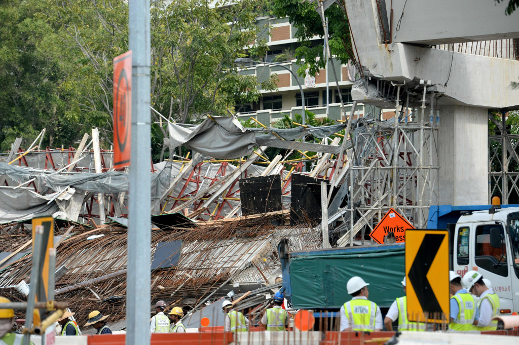 Para pekerja berdiri di dekat lokasi ambruknya konstruksi jalan layang. Mayoritas pekerja konstruksi di Singapura adalah warga negara asing.