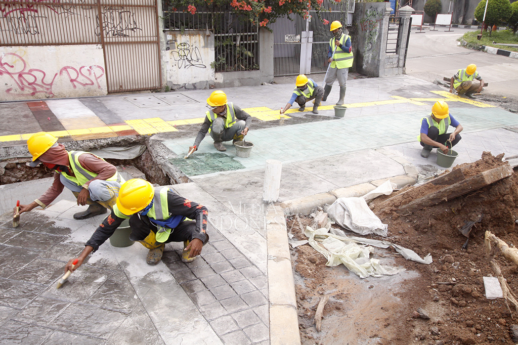 Mereka mengebor, memasang batako, memasang kerangka besi, hingga mengecat bagian trotoar yang sudah hampir selesai.