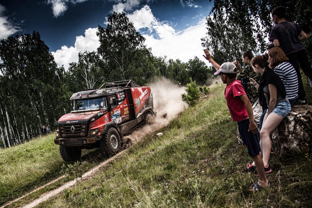 Truk Renault ngebut di jalan setapak keluar dari dalam hutan. 