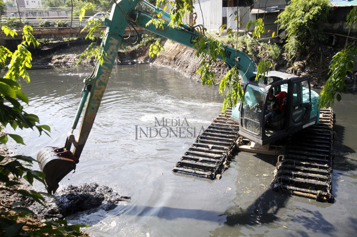 Petugas menggunakan alat berat mengeruk endapan sampah bercampur lumpur di bantaran Kali Sunter, Jalan Perintis Kemerdekaan, Pulogadung, Jakarta Timur.