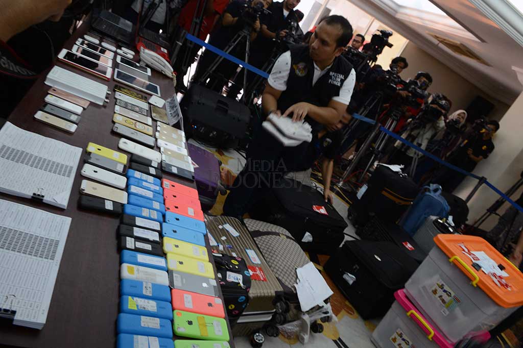 Polisi menggelar barang bukti berupa sejumlah ponsel, kartu pengenal, serta perangkat elektronik lainnya.