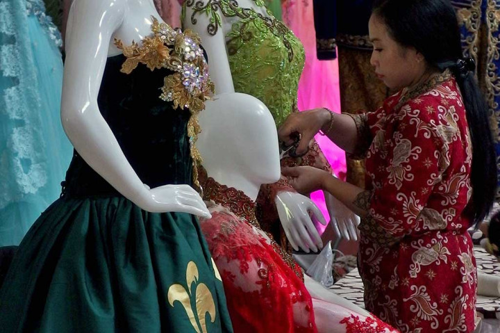 Penjaga stan menata busana pengantin tradisional modifikasi pada sebuah patung peraga, dalam pameran Pernikahan Tradisional 2017 di Semarang.