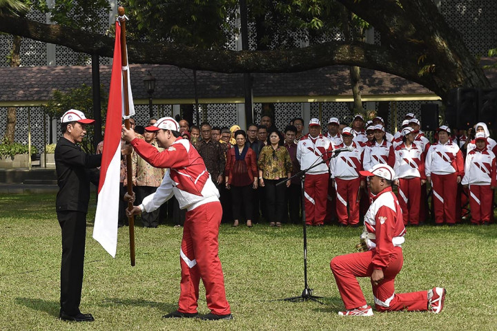 Presiden Joko Widodo menyerahkan bendera Merah Putih kepada Ketua Kontingen Indonesia SEA Games XXIX Malaysia Aziz Syamsuddin saat upacara pelepasan di halaman Kompleks Istana Kepresidenan, Jakarta.