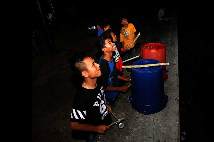 Sejumlah warga memukul ember, kaleng dan botol plastik saat gerhana bulan di Suwawa, Kabupaten Bone Bolango, Gorontalo, Selasa (8/8/2017) dini hari. Tradisi memukul berbagai benda di daerah tersebut dilakukan saat gerhana bulan atau gerhana matahari. ANTARA/Adiwinata Solihin