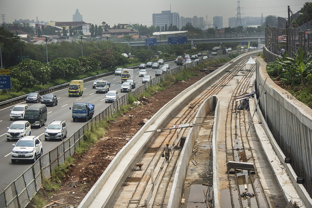 Kendaraan melintas di samping proyek pembangunan kereta ringan atau Light Rail Transit (LRT) rute Cibubur-Cawang di Tol Jagorawi, Cibubur, Jakarta.