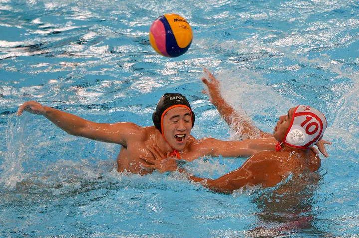 Atlet polo air Indonesia Ridjkie Mulya (kanan) berebut bola dengan atlet polo air Malaysia Tan Tsien Hann.