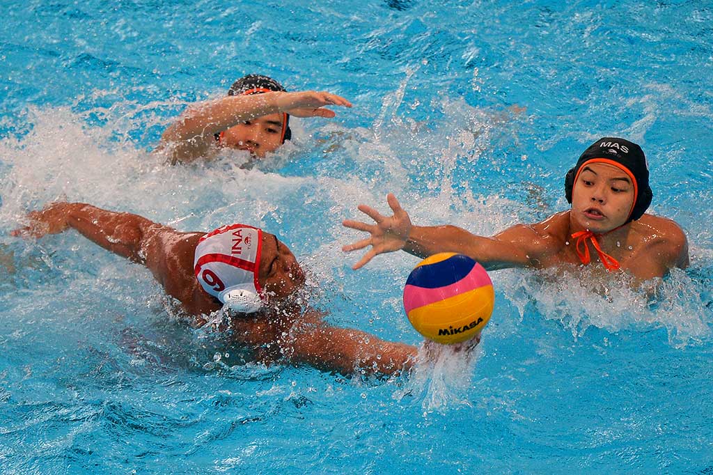Atlet polo air Indonesia Delvin Felliciano (tengah) berebut bola dengan atlet polo air Malaysia Leung Chee Liang (kiri) dan Toh Yi Xiang. 