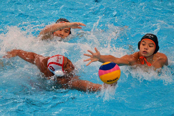 Atlet polo air Indonesia Delvin Felliciano (tengah) berebut bola dengan atlet polo air Malaysia Leung Chee Liang (kiri) dan Toh Yi Xiang. 