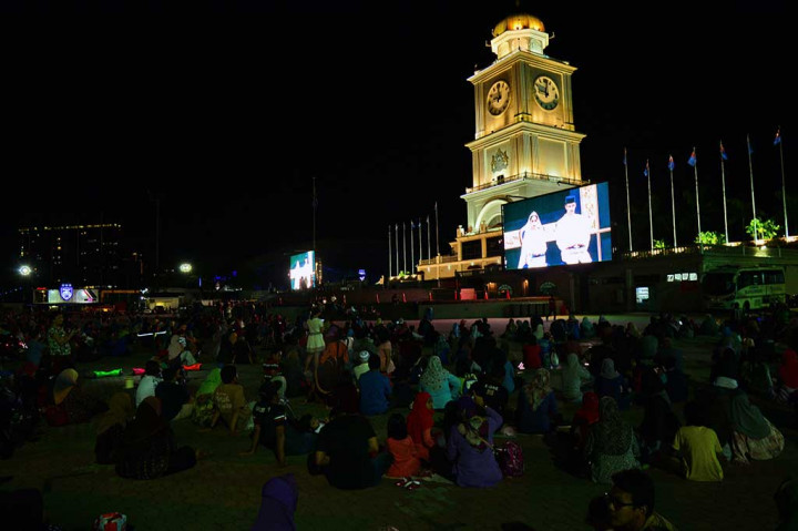 Warga menyaksikan seremoni pernikahan putri Sultan Johor lewat layar lebar yang dipasang di Dataran Bandaraya (alun-alun kota) di Johor Baru.