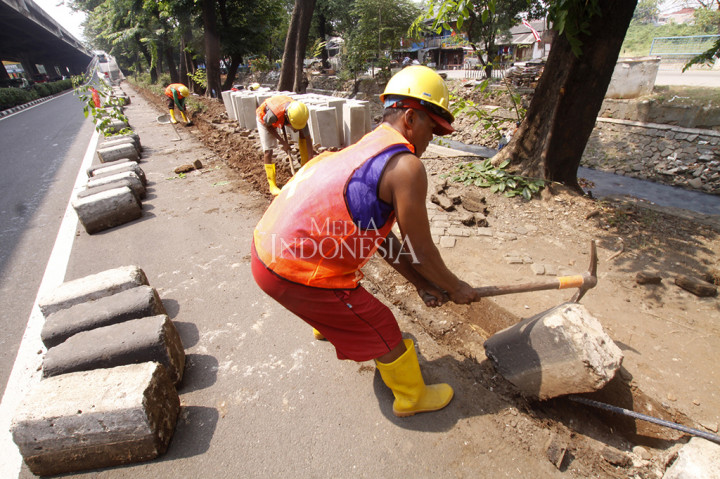 Pekerja membongkar beton kanstin trotoar di Jalan Ahmad Yani, Jakarta Timur.