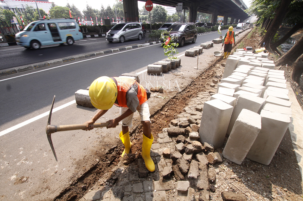 Pekerja membongkar beton kanstin trotoar di Jalan Ahmad Yani, Jakarta Timur.