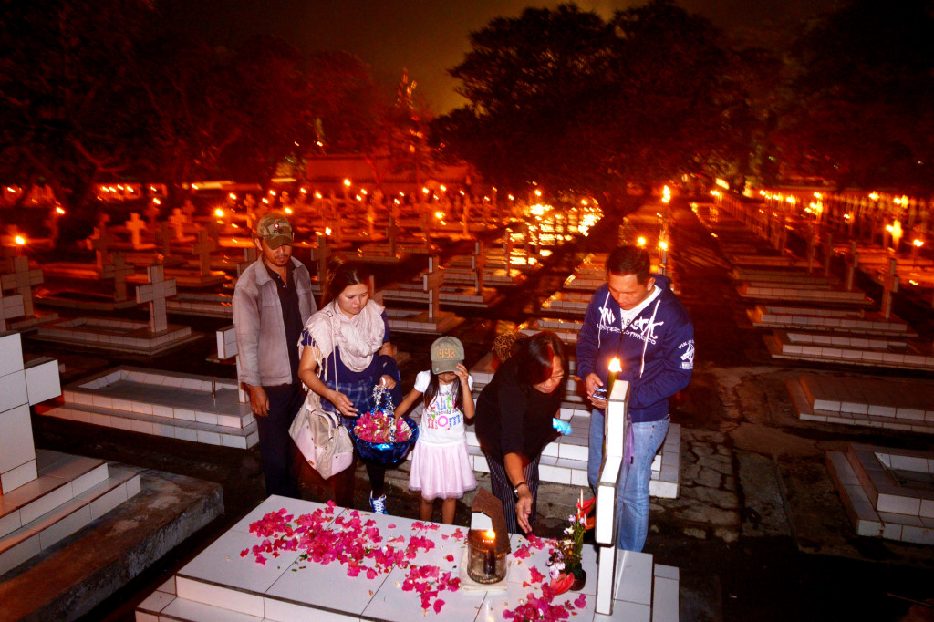 Sejumlah anggota keluarga menaburkan bunga di salah satu makam di TMP Kairagi, Manado. Kegiatan renungan sucipada malam sebelum hari peringatan hari kemerdekaan bertujuan menghormati, mengenang jasa dan pengorbanan para pahlawan. ANTARA FOTO/Adwit B Pramono