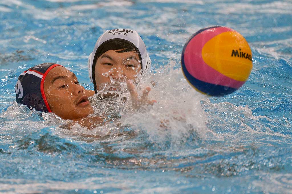 Atlet polo air Indonesia Delvin Pelliciano (kiri) berebut bola dengan atlet polo air Singapura Yu Junjie.