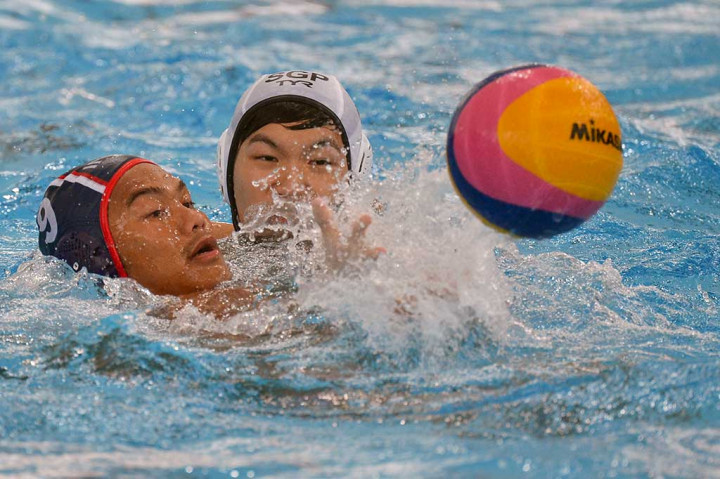 Atlet polo air Indonesia Delvin Pelliciano (kiri) berebut bola dengan atlet polo air Singapura Yu Junjie.