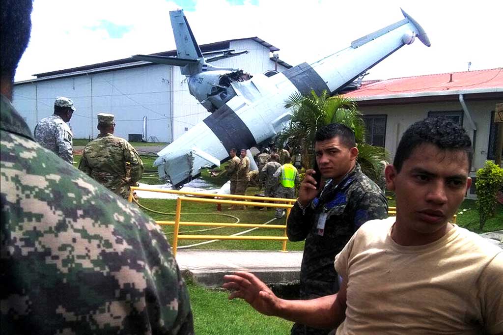 Personel militer dan petugas pemadam kebakaran berusaha mengevakuasi reruntuhan pesawat militer milik Honduras yang jatuh di Palmerola.