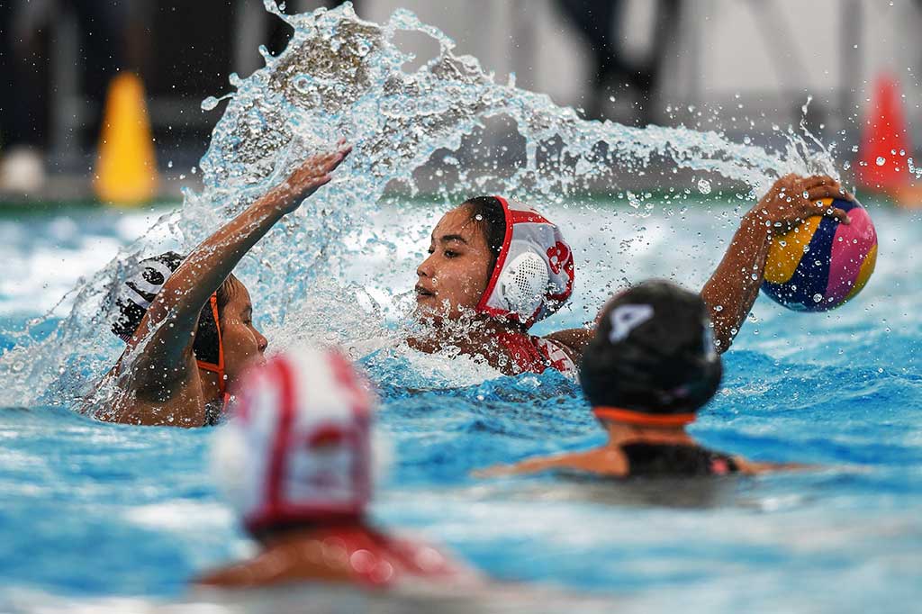 Atlet polo air putri Indonesia Hudaidah Kadir berusaha mempertahankan bola di tangannya dari hadangan pemain tuan rumah.