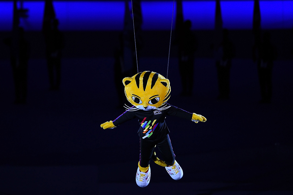 Usai penari undur diri dari tengah lapangan. Para penonton disajikan aksi Rimau, maskot SEA Games 2017, terbang di udara. Ketika turun, maskot berwajah Harimau itu disambut kembali oleh para penari. AFP/ MANAN VATSYAYANA