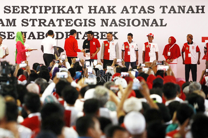 Presiden Joko Widodo menyerahkan sertipikat tanah kepada Gubernur DKI Jakarta Djarot Syaiful Hidayat dan perwakilan penerima sertifikat pada acara 'Penyerahan Sertifikat Hak Atas Tanah, Program Strategis Nasional Se-Jabodetabek' di Lapangan Park & Ride, Jakarta. MI/PANCA SYURKANI