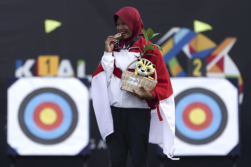 Atlet panahan Indonesia Diananda Choirunnisa membawa bendera merah putih seusai mengalahkan lawannya asal Filipina Nicole Marie Tagle pada final nomor recurve putri di Synthetic Turf Fild, Kawasan Bukit Jalil, Malaysia.
