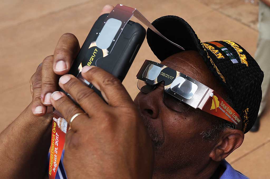 Warga mengabadikan fenomena gerhana matahari dengan kamera ponselnya di Myrthe Beach, Couth Carolina.