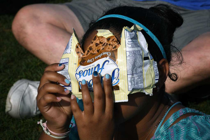 Seorang wanita dengan peralatan seadanya berusaha melihat proses gerhana matahari total di Observatorium Griffith di Los Angeles, California.