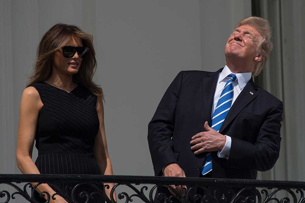 Presiden AS Donald Trump menatap langit dengan menyipikan mata saat melihat proses gerhana matahari total dari balkon di Gedung Putih, Washington DC, Senin (21/8/2017) waktu setempat.