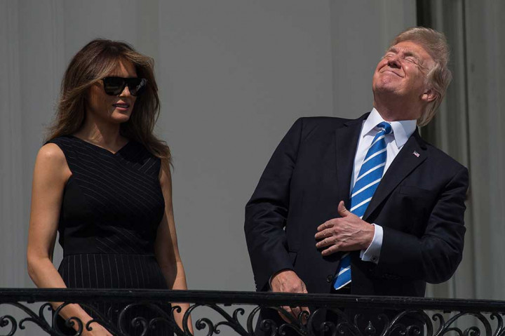 Presiden AS Donald Trump menatap langit dengan menyipikan mata saat melihat proses gerhana matahari total dari balkon di Gedung Putih, Washington DC, Senin (21/8/2017) waktu setempat.