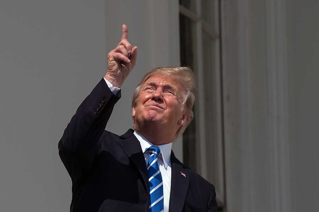 Trump sempat menunjuk ke langit saat melihat fenomena gerhana matahari tanpa menggunakan kacamata pelindung.