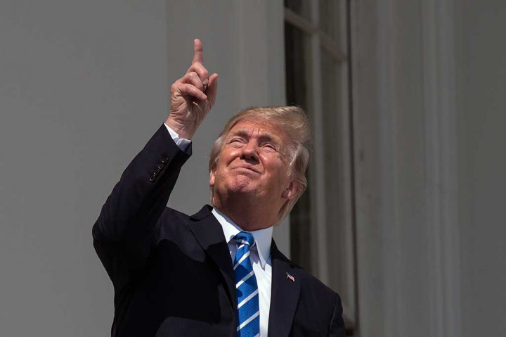 Trump sempat menunjuk ke langit saat melihat fenomena gerhana matahari tanpa menggunakan kacamata pelindung.