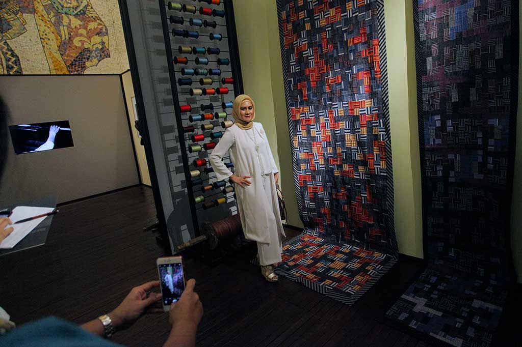 Pengunjung berfoto di dekat koleksi kain lurik koleksi Edward Hutabarat.