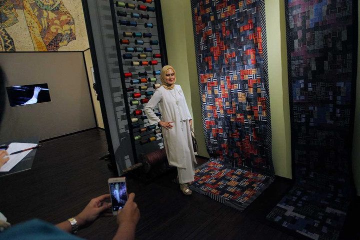 Pengunjung berfoto di dekat koleksi kain lurik koleksi Edward Hutabarat.