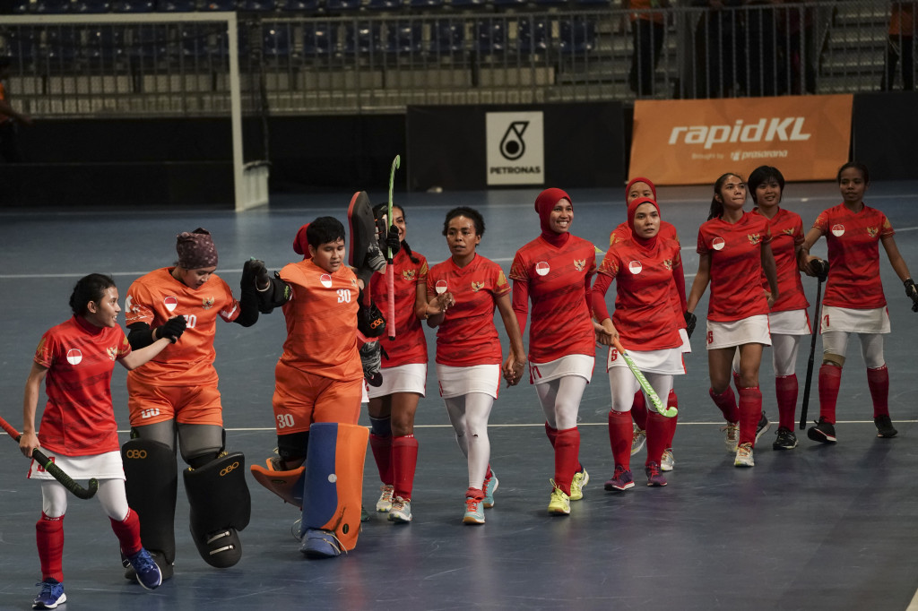Tim hoki indoor putri Indonesia tersenyum gembira dan bergandengan tangan mengelilingi arena MITEC, Kuala Lumpur, usai laga final melawan Thailand.