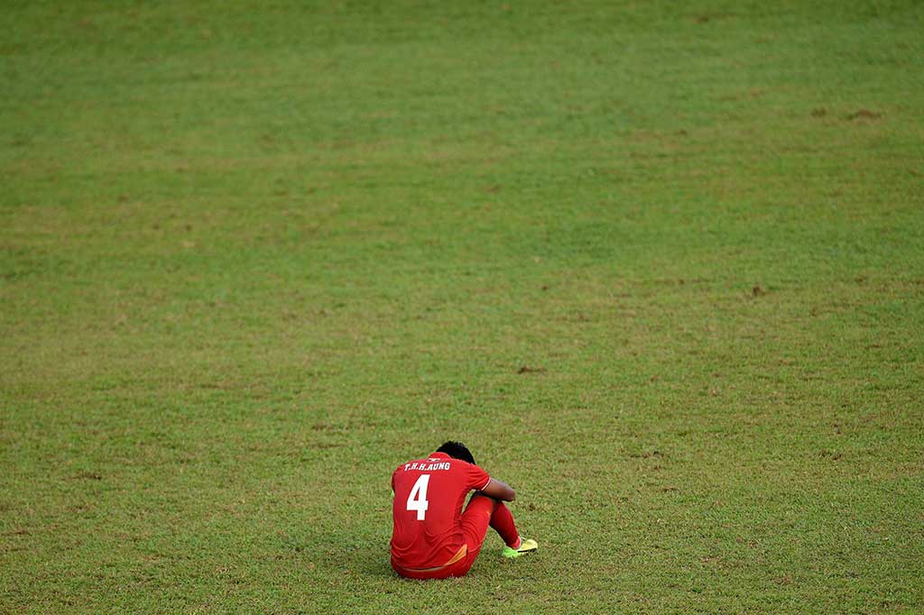 Pemain Myanmar Thiha Htet Aung tertunduk lesu di tengah lapangan.