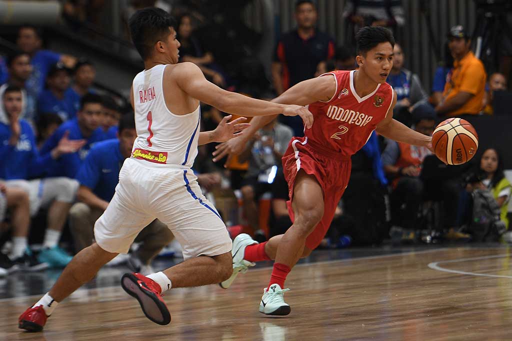 Pebasket Indonesia Hardianus Lakudu berusaha melewati pebasket Filipina Kiefer Isaac Ravena.