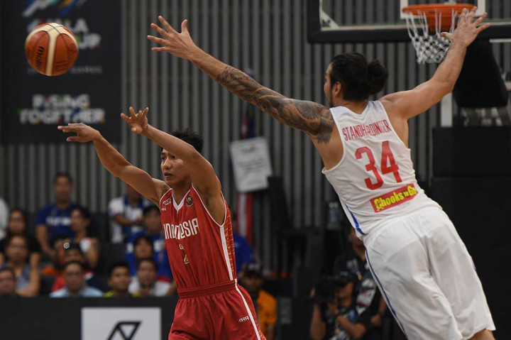Pebasket Indonesia Hardianus Lakudu (kiri) mengoper bola dibayangi pebasket Filipina Christian Karl Standhardinger.