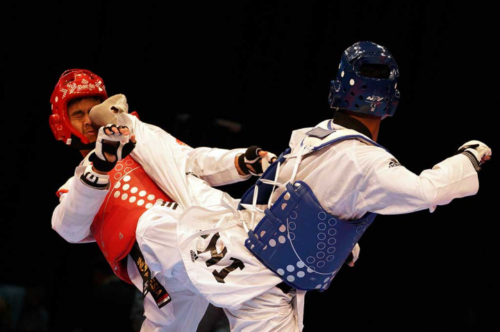 Dinggo Ardian Prayogo (kiri) mendapat tendangan dari atlet taekwondo Filipina Morrison Samuel. Dinggo meraih perak setelah kalah dari lawannya 18-28.