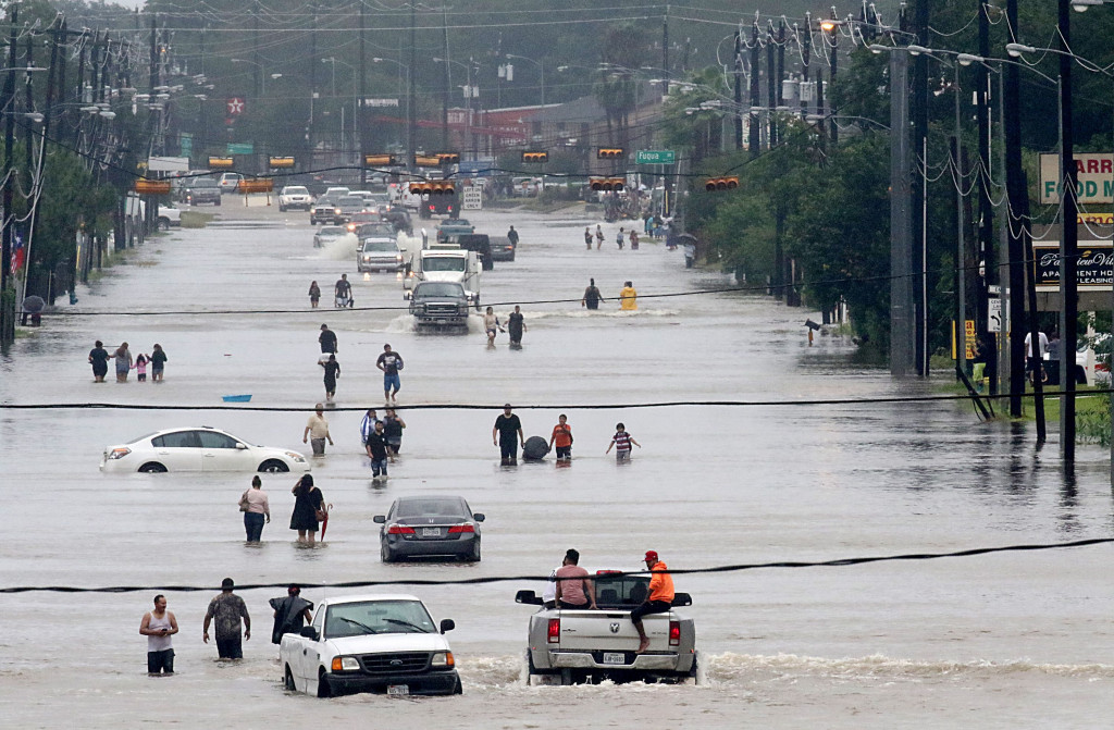 Warga menerobos banjir menuju tempat pengungsian. Banjir bandhang ini adalah dampak dari mengamuknya badai tropis harvey yang menyerang Texas sehari sebelumnya. AFP PHOTO / Thomas B. Shea