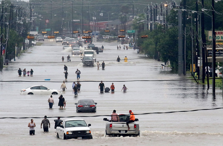 Warga menerobos banjir menuju tempat pengungsian. Banjir bandhang ini adalah dampak dari mengamuknya badai tropis harvey yang menyerang Texas sehari sebelumnya. AFP PHOTO / Thomas B. Shea