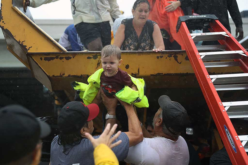 Seorang balita dibantu untuk menaiki sebuah truk penyelamat sebelum dievakuasi ke tempat pengungsian bersama keluarganya. AFP/Joe Raedle/Getty Images