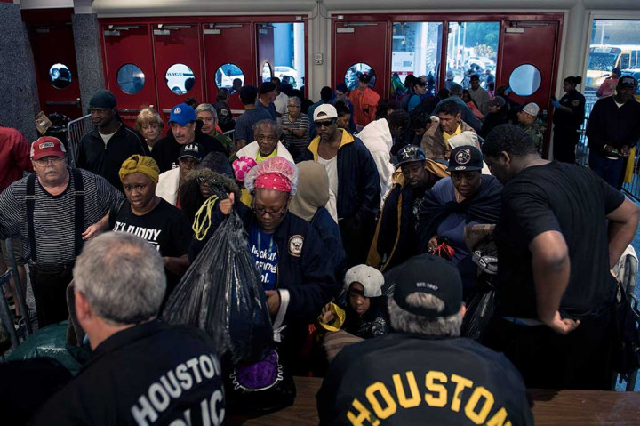 Orang-orang menunggu untuk diperiksa polisi sebelum memasuki tempat penampungan di George R. Brown Convention Center. AFP/Brendan Smialowski