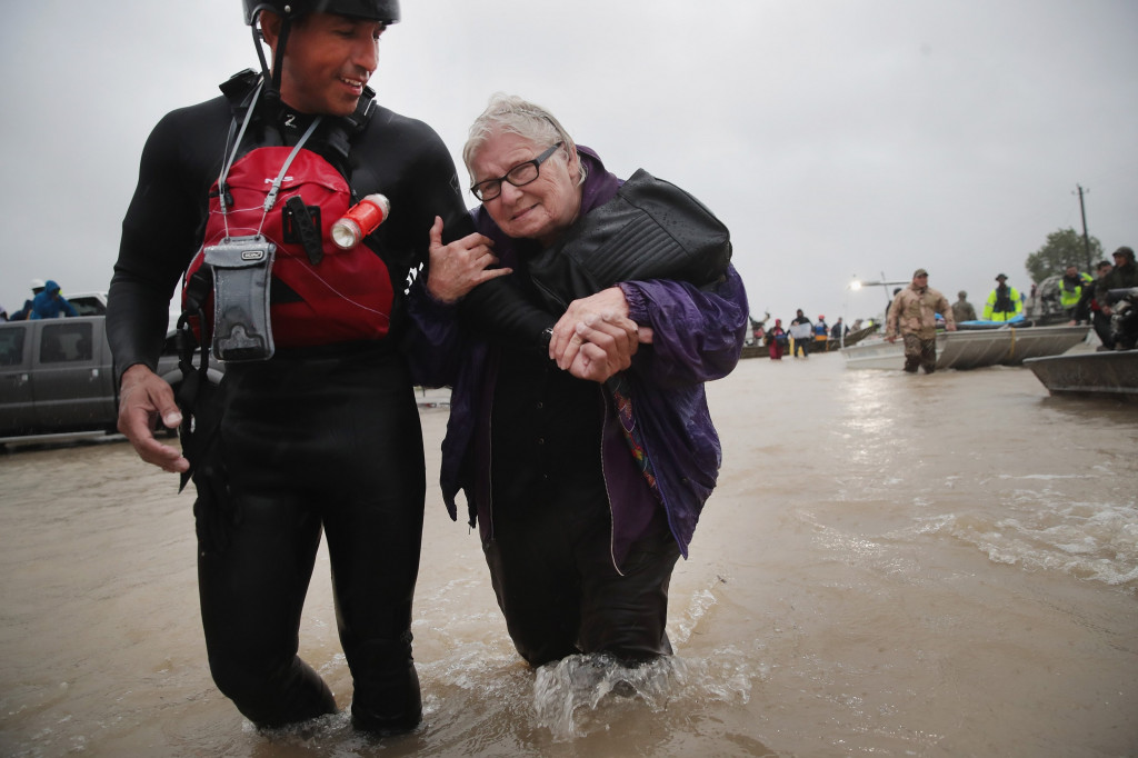 Barb Davis (74) dibantu petugas SAR meninggalkan rumahnya yang terendam banjir. Jumlah korban badai yang terjadi dua hari lalu belum dipastikan. Scott Olson/Getty Images/AFP