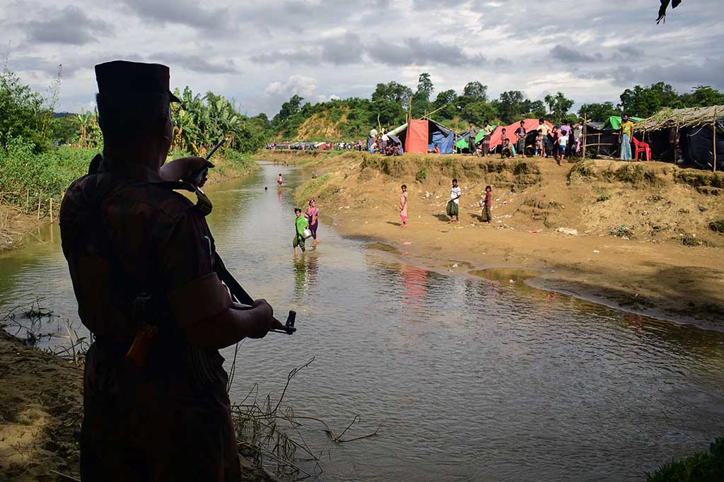 Seorang penjaga perbatasan Bangladesh memerintahkan pengungsi Rohingya untuk kembali ke sisi Myanmar, di sebuah kanal kecil perbatasan kedua negara.