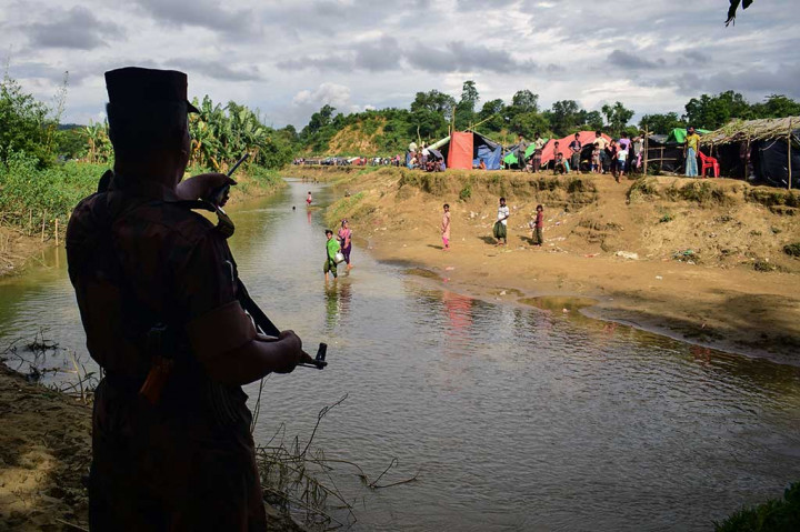 Seorang penjaga perbatasan Bangladesh memerintahkan pengungsi Rohingya untuk kembali ke sisi Myanmar, di sebuah kanal kecil perbatasan kedua negara.
