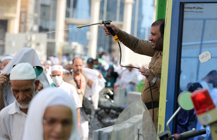 Seorang polisi Saudi menyemprotkan air untuk menyegarkan jemaah calon haji yang sedang kegerahan di tengah kepadatan jalan dan paparan suhu tinggi. AFP Photo/Karim Sahib