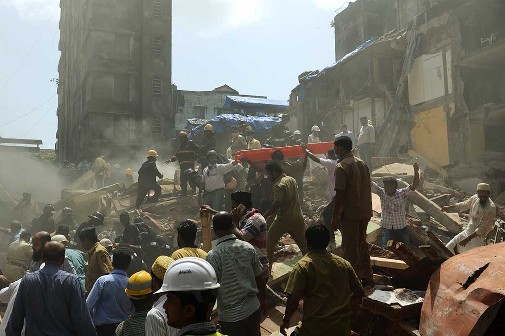 Puluhan petugas berusaha mengevakuasi para korban di reruntuhan gedung lima lantai di Mumbai, India, Kamis (31/8/2017).