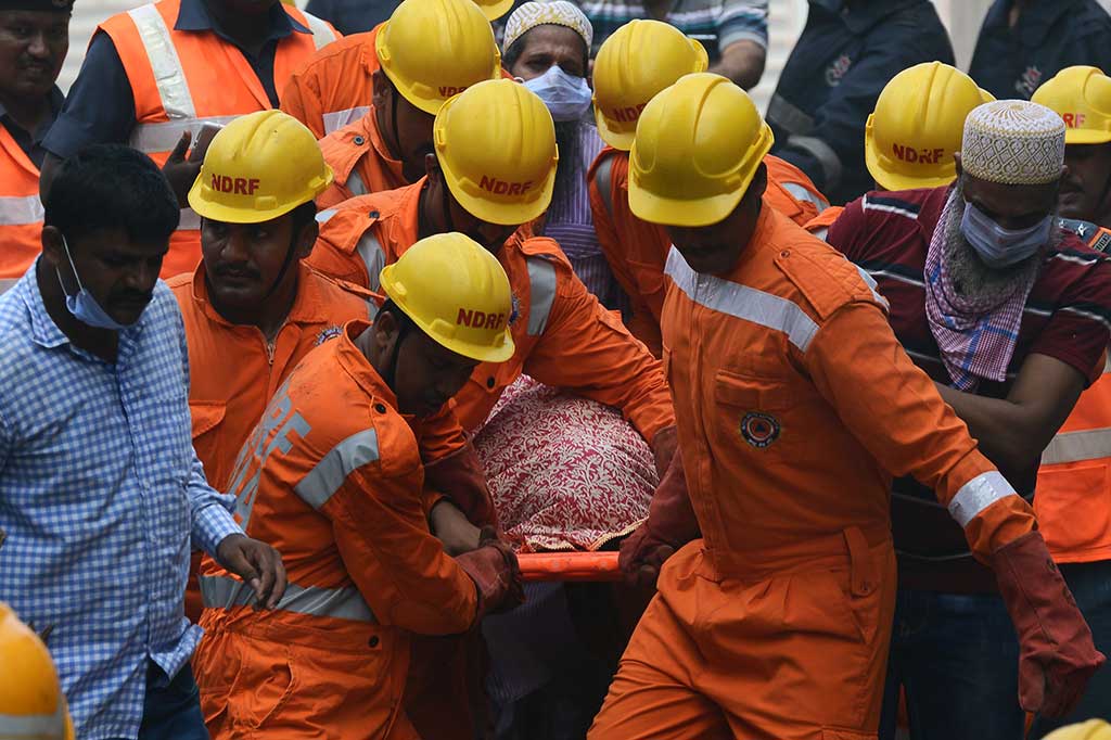 Petugas mengevakuasi jenazah korban dari reruntuhan gedung.