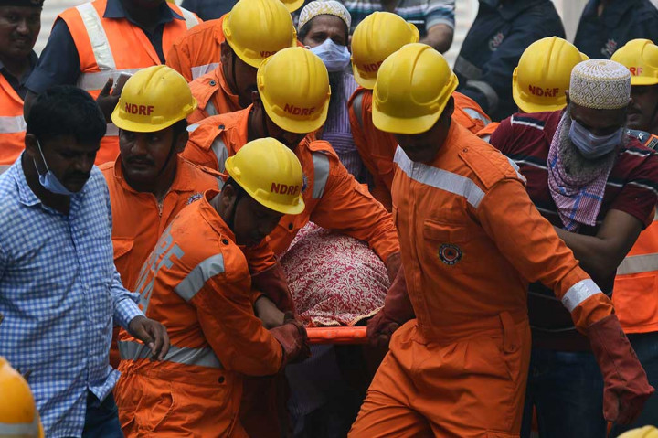 Petugas mengevakuasi jenazah korban dari reruntuhan gedung.