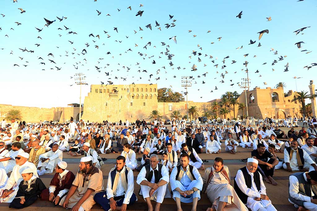 Burung beterbangan saat umat Muslim Libya mendengarkan khotbah Iduladha di Martir Square, Tripoli. AFP/Mahmud Turkia